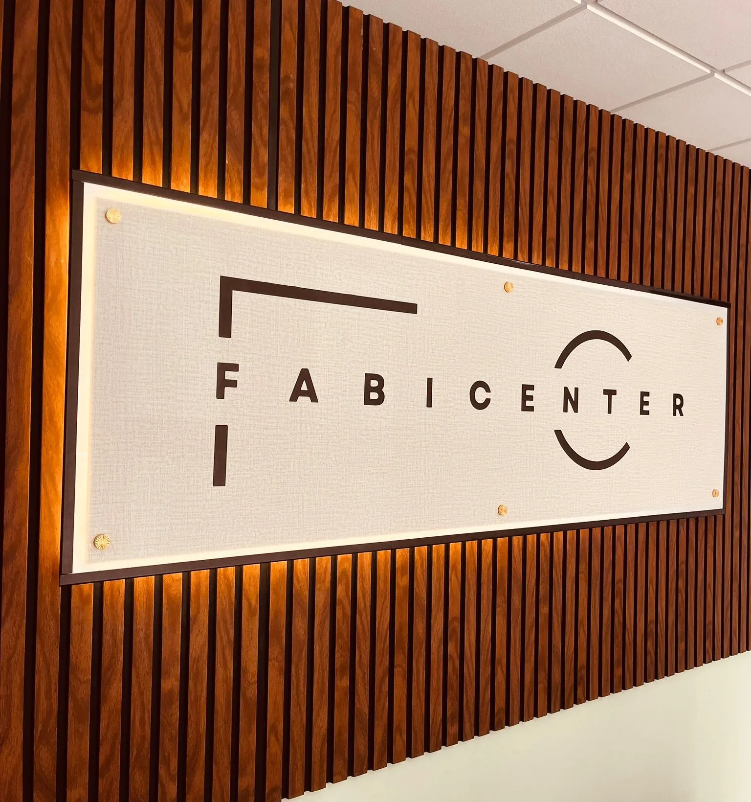 Cartel de FABICENTER con su logo sobre una pared de madera en el local de Playa de la Arena